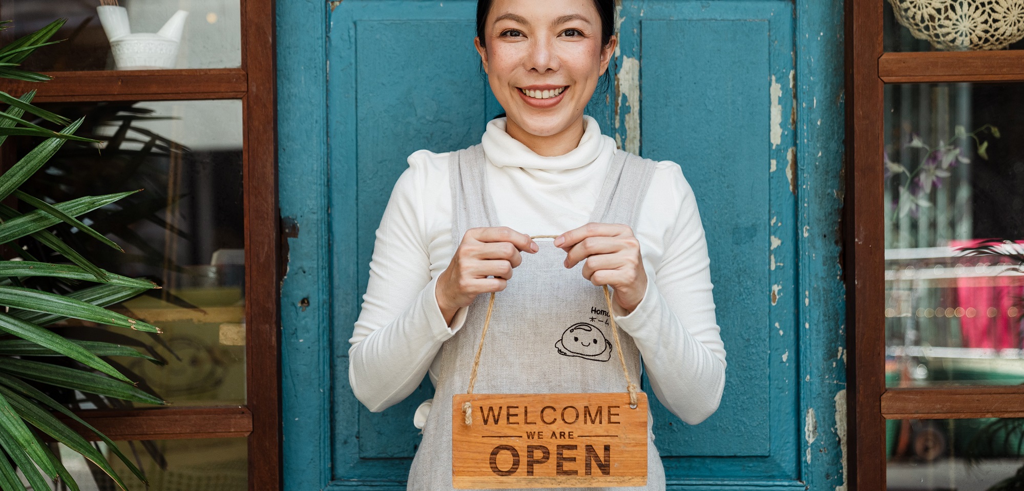 Women holding "welcome we are open" sign