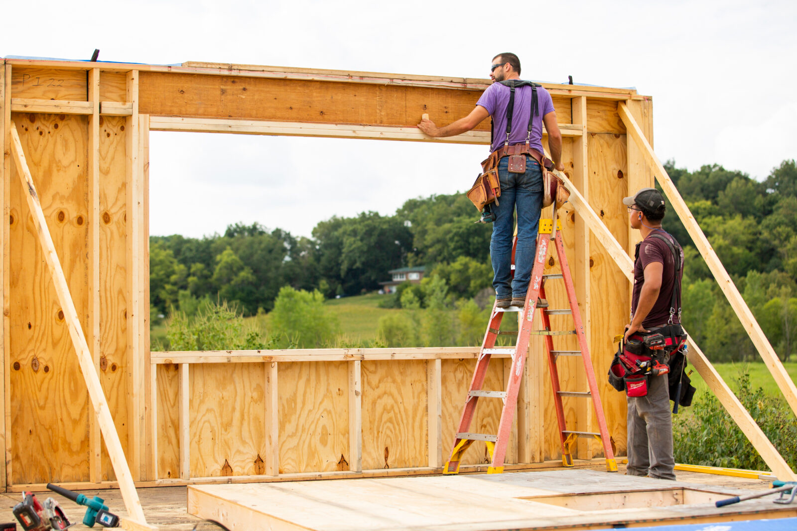 Construction professionals frame out the exterior wall of a house with a large window